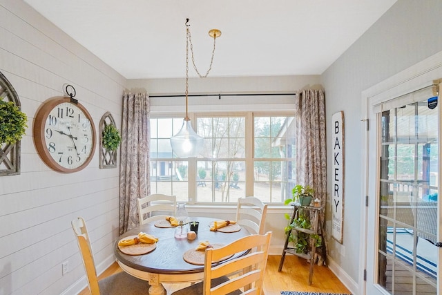 dining space with wood-type flooring and wooden walls