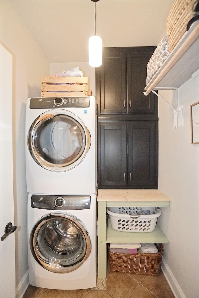 laundry room featuring cabinets, stacked washer and clothes dryer, and tile patterned floors