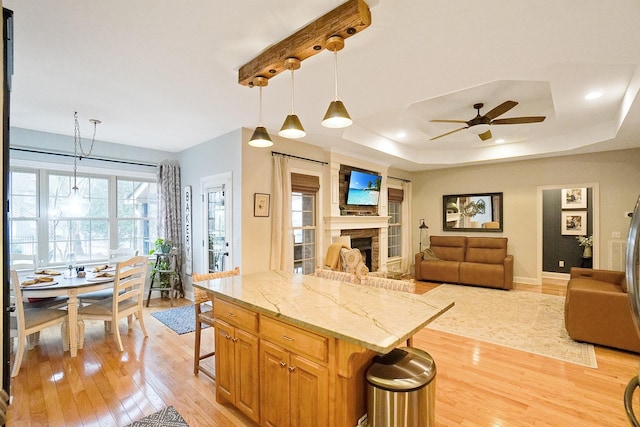 kitchen featuring light stone countertops, a breakfast bar area, pendant lighting, and light hardwood / wood-style floors