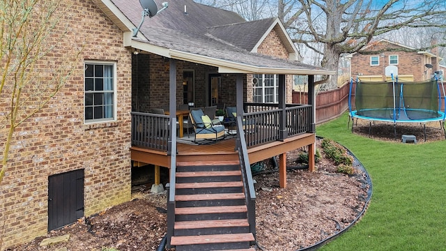 deck featuring a trampoline and a lawn