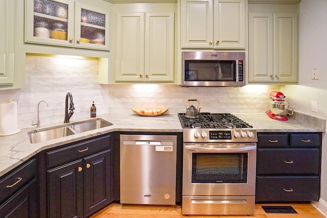 kitchen featuring light stone countertops, appliances with stainless steel finishes, sink, and decorative backsplash