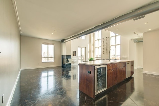 kitchen with sink, beverage cooler, and a center island with sink