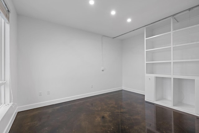 empty room featuring concrete floors and built in shelves