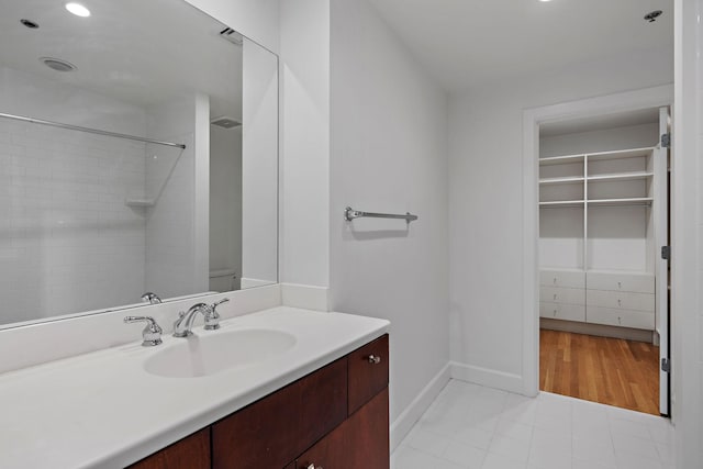 bathroom with tiled shower and vanity