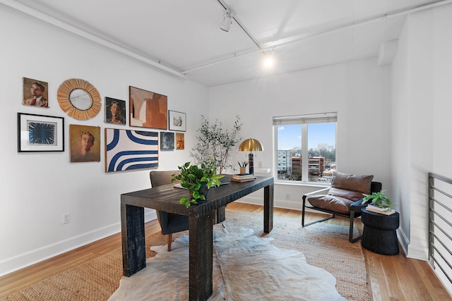 home office with wood-type flooring and track lighting