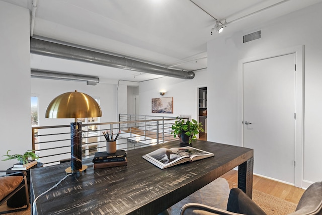 office space with rail lighting and hardwood / wood-style floors