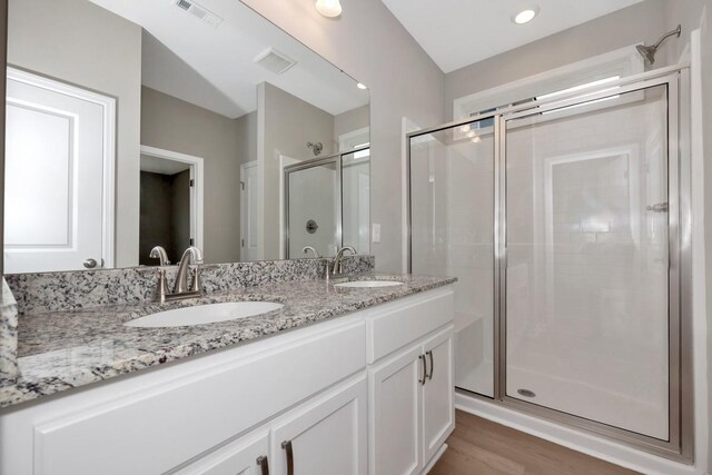 bathroom with vanity, hardwood / wood-style floors, and a shower with door