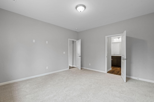 unfurnished bedroom featuring ensuite bathroom and carpet flooring