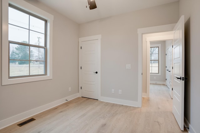 empty room with ceiling fan and light hardwood / wood-style flooring