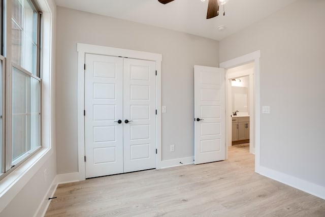 unfurnished bedroom with ceiling fan, a closet, and light wood-type flooring