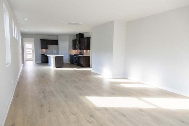 unfurnished living room featuring sink and light hardwood / wood-style floors