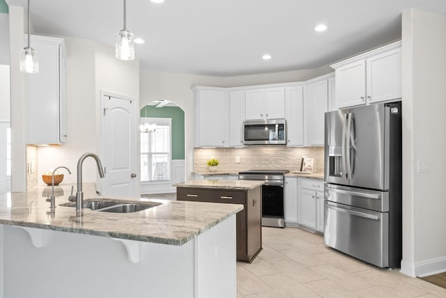 kitchen with sink, white cabinetry, appliances with stainless steel finishes, a kitchen island, and pendant lighting