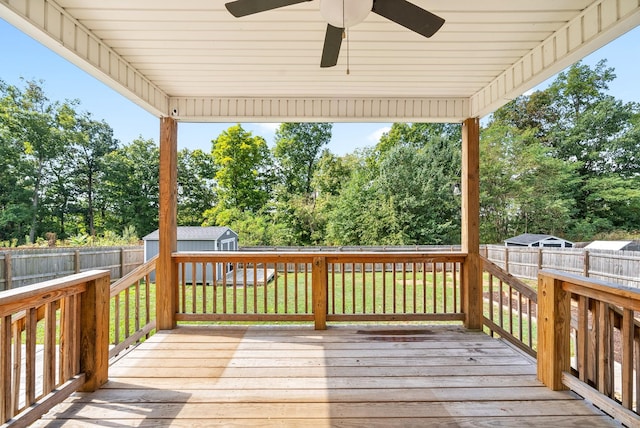 wooden terrace featuring a lawn, ceiling fan, and a storage unit