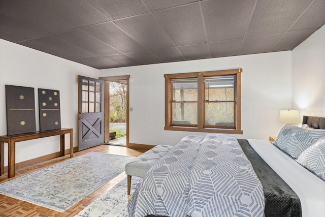 bedroom with multiple windows, access to exterior, a paneled ceiling, and parquet flooring