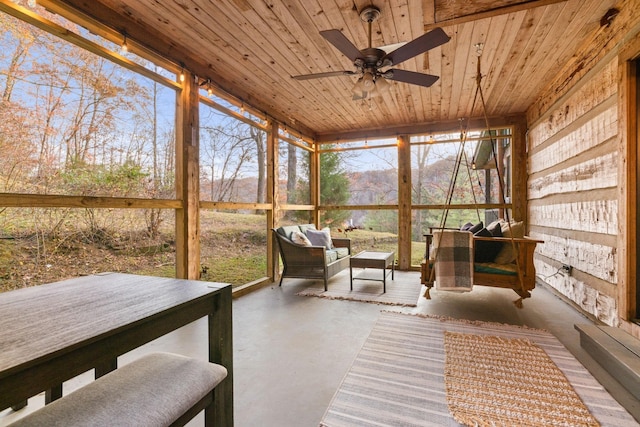 sunroom with wood ceiling, ceiling fan, and a mountain view