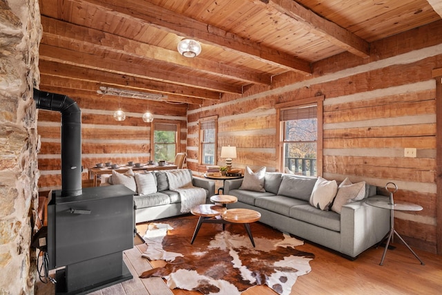 living room featuring wooden walls, a wood stove, wooden ceiling, beam ceiling, and light hardwood / wood-style flooring