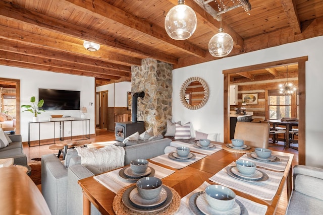 living room with hardwood / wood-style flooring, a wood stove, wooden ceiling, and beamed ceiling