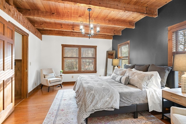 bedroom featuring beamed ceiling, light wood-type flooring, wooden ceiling, and a chandelier