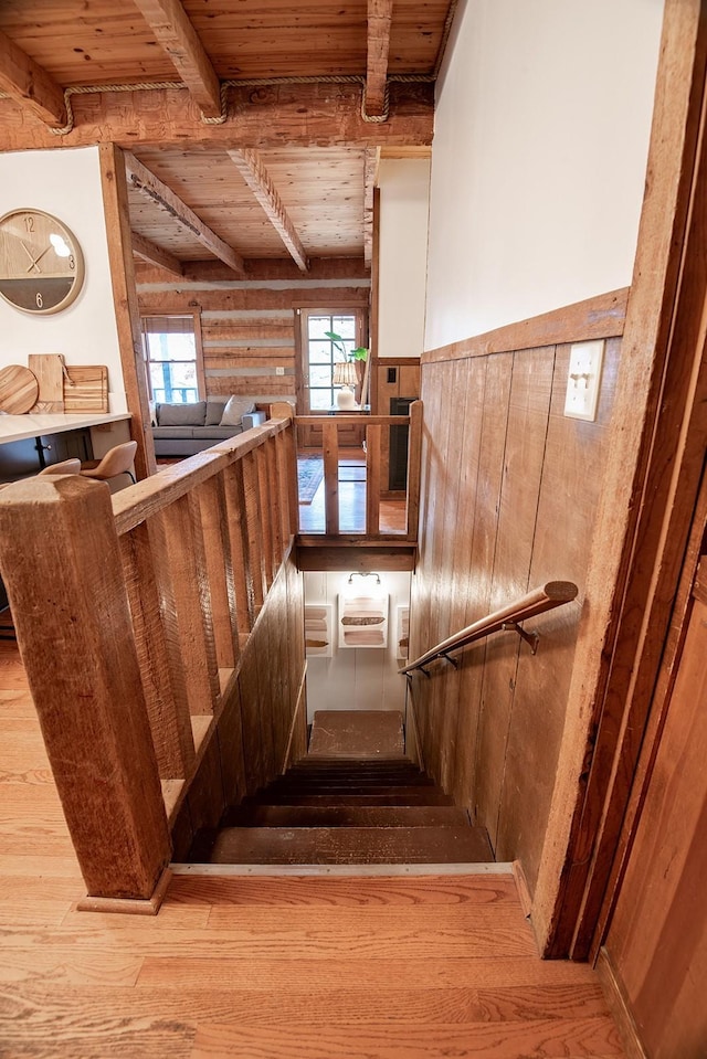 staircase featuring beam ceiling, a wall unit AC, log walls, and wood ceiling