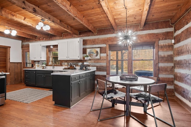 kitchen featuring decorative light fixtures, beamed ceiling, white cabinets, wood ceiling, and light hardwood / wood-style flooring