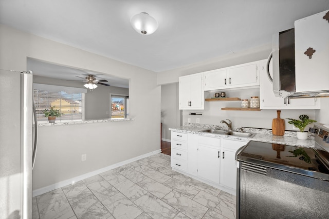 kitchen with appliances with stainless steel finishes, white cabinetry, sink, ceiling fan, and light stone countertops