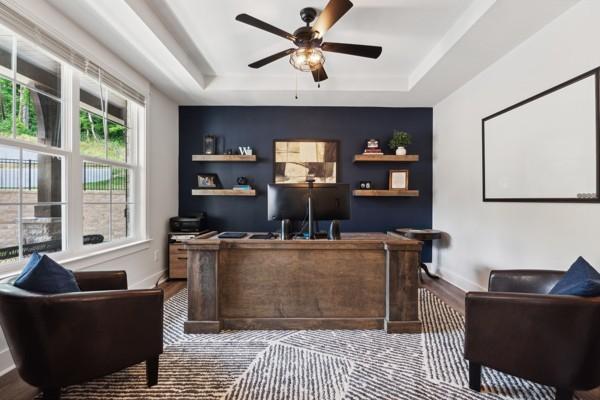 home office featuring a raised ceiling, hardwood / wood-style floors, and ceiling fan