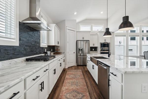 kitchen featuring appliances with stainless steel finishes, decorative light fixtures, white cabinetry, dark hardwood / wood-style flooring, and exhaust hood