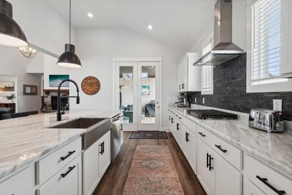 kitchen featuring appliances with stainless steel finishes, decorative light fixtures, white cabinetry, light stone countertops, and wall chimney exhaust hood