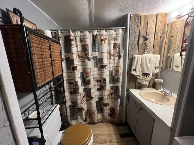 bathroom with toilet, a textured ceiling, vanity, curtained shower, and hardwood / wood-style flooring