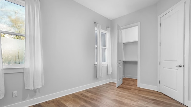 unfurnished bedroom featuring a walk in closet and light wood-type flooring