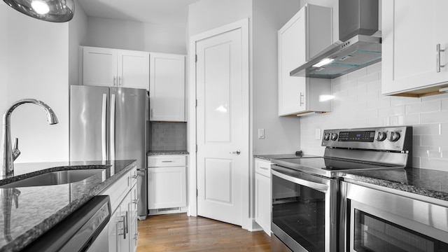 kitchen featuring white cabinets, stainless steel appliances, sink, and wall chimney exhaust hood