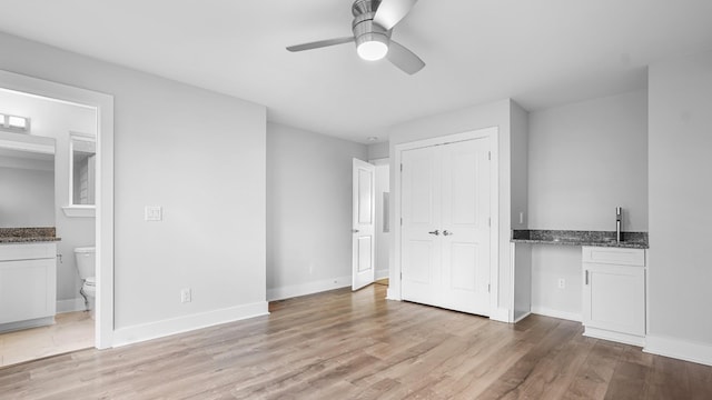 unfurnished bedroom featuring ceiling fan, ensuite bath, a closet, and light hardwood / wood-style flooring