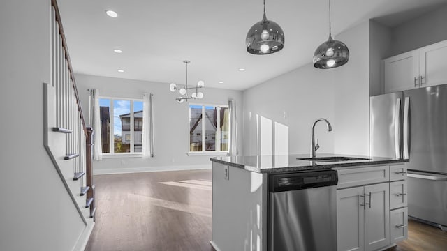 kitchen with pendant lighting, sink, appliances with stainless steel finishes, an island with sink, and dark hardwood / wood-style flooring