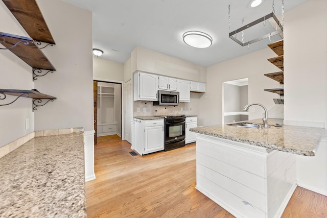 kitchen featuring black electric range oven, sink, light hardwood / wood-style flooring, light stone counters, and white cabinets