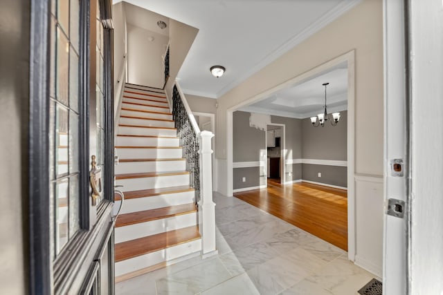 foyer with crown molding, a chandelier, and a raised ceiling