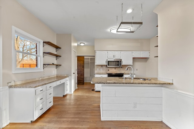 kitchen featuring light stone countertops, built in desk, white cabinets, and kitchen peninsula