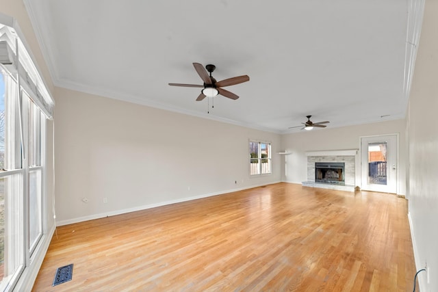 unfurnished living room with ornamental molding, light wood-type flooring, ceiling fan, and a fireplace