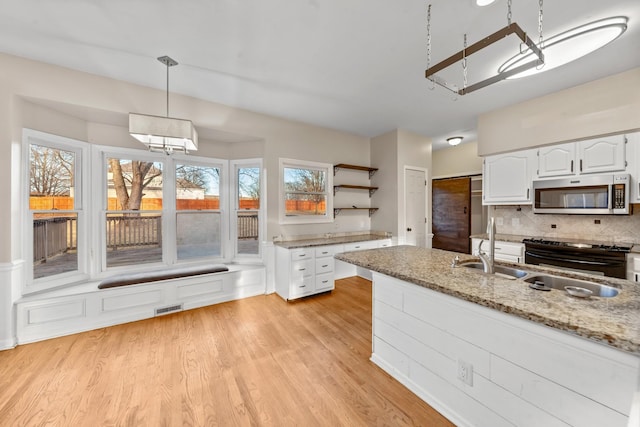 kitchen with white cabinetry, hanging light fixtures, black electric range, light stone countertops, and light hardwood / wood-style floors