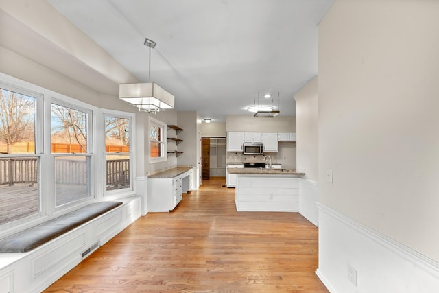 kitchen featuring pendant lighting, sink, light hardwood / wood-style flooring, and white cabinets