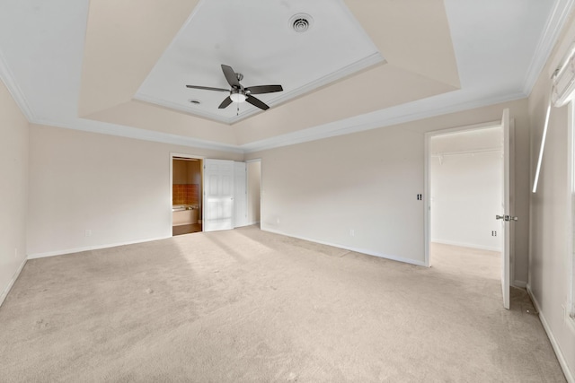 spare room with light carpet, a tray ceiling, crown molding, and ceiling fan