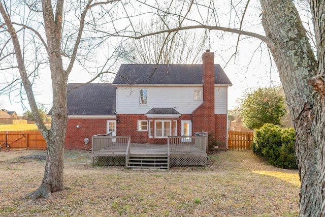 rear view of house featuring a wooden deck and a yard