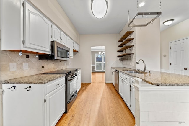 kitchen with sink, appliances with stainless steel finishes, white cabinetry, light stone counters, and decorative backsplash