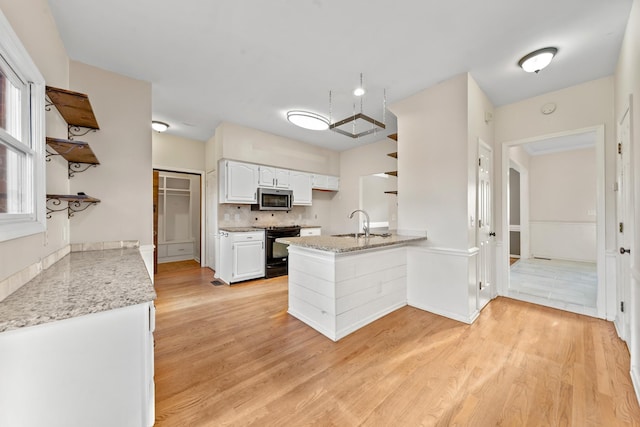 kitchen with white cabinetry, light stone counters, light hardwood / wood-style floors, black range with electric cooktop, and kitchen peninsula