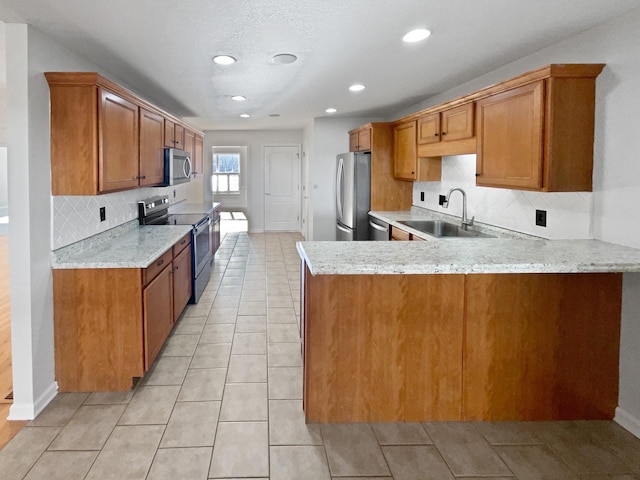 kitchen with sink, appliances with stainless steel finishes, light stone countertops, light tile patterned flooring, and kitchen peninsula