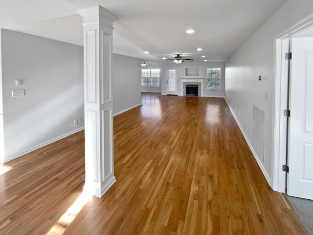 unfurnished living room featuring hardwood / wood-style floors, ceiling fan, and ornate columns