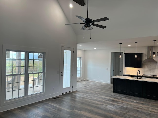 kitchen with dark wood-type flooring, sink, hanging light fixtures, wall chimney range hood, and backsplash