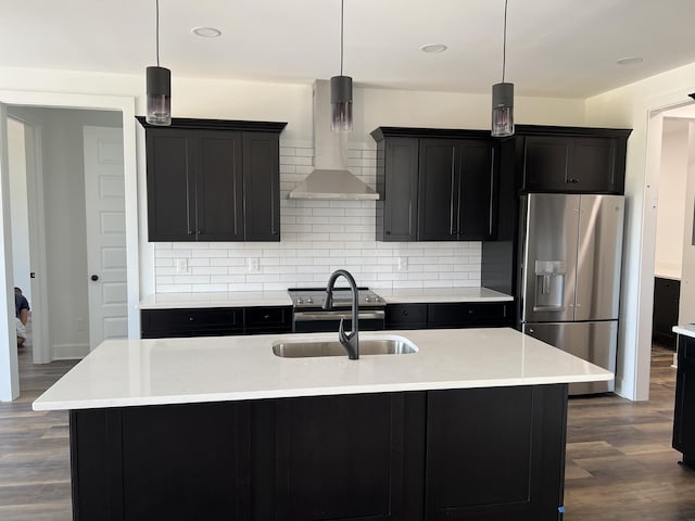 kitchen featuring stainless steel appliances, decorative light fixtures, sink, and a center island with sink