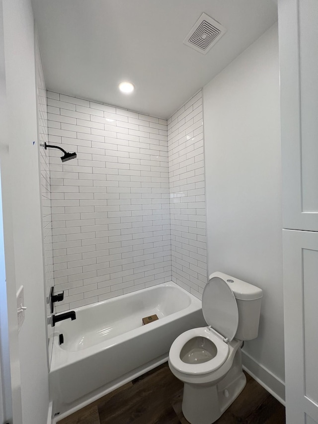 bathroom with tiled shower / bath, wood-type flooring, and toilet