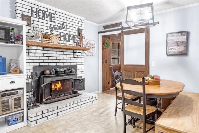 dining room with a fireplace, ornamental molding, a barn door, and a textured ceiling