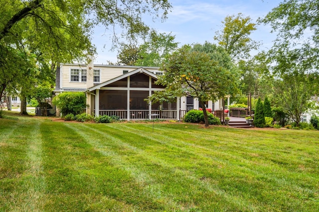 back of property with a yard, a deck, and a sunroom